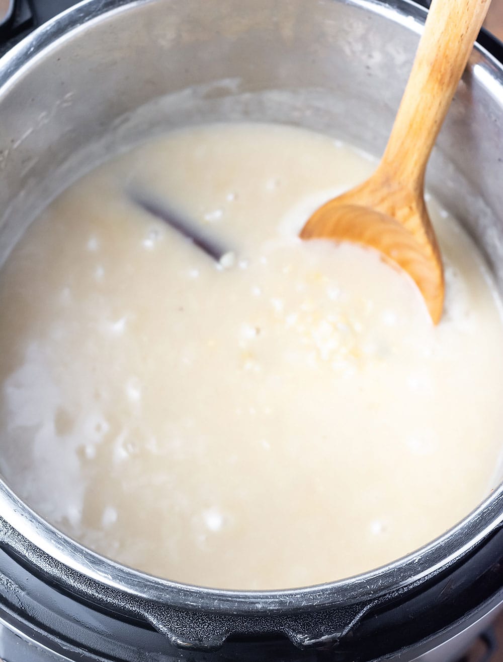 Brown rice pudding in an Instant pot with a wooden spoon used for stirring