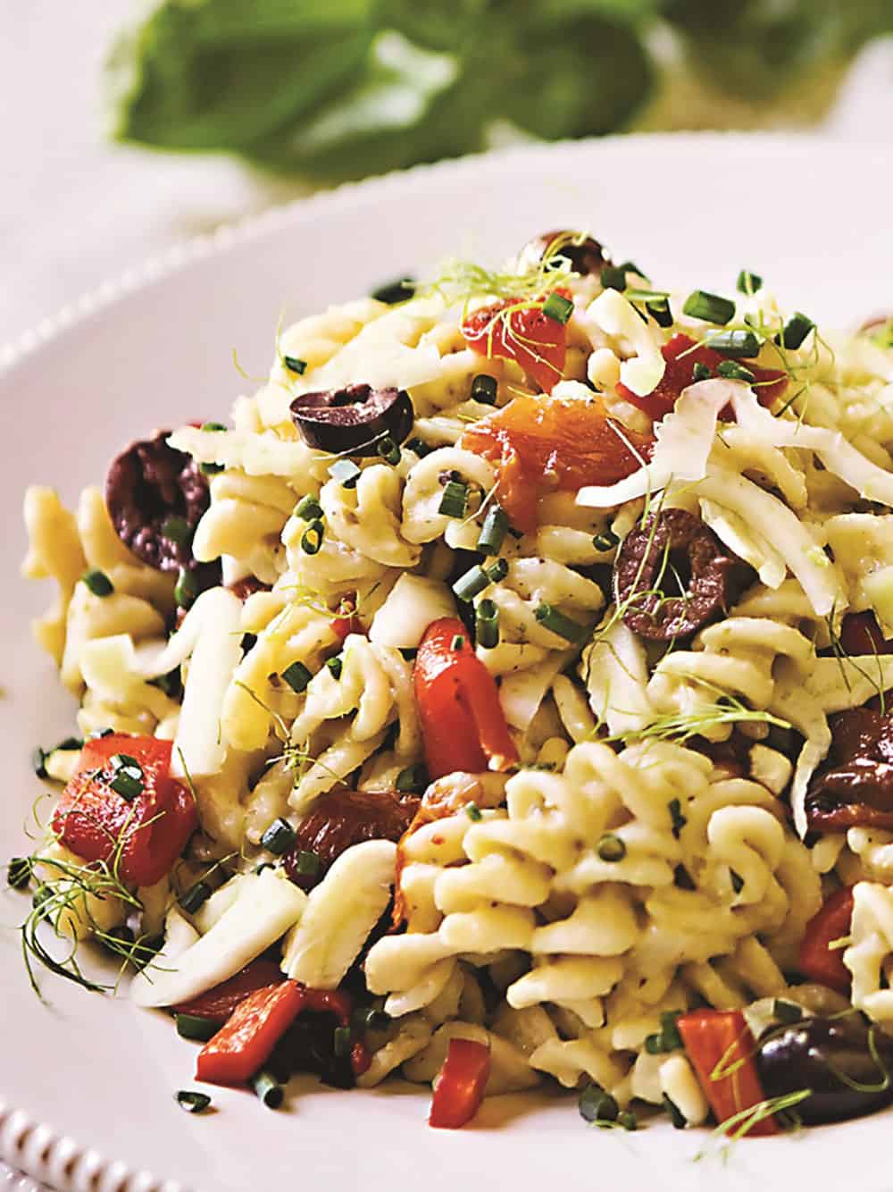 Hummus pasta salad with black olives, tomatoes and sprouts