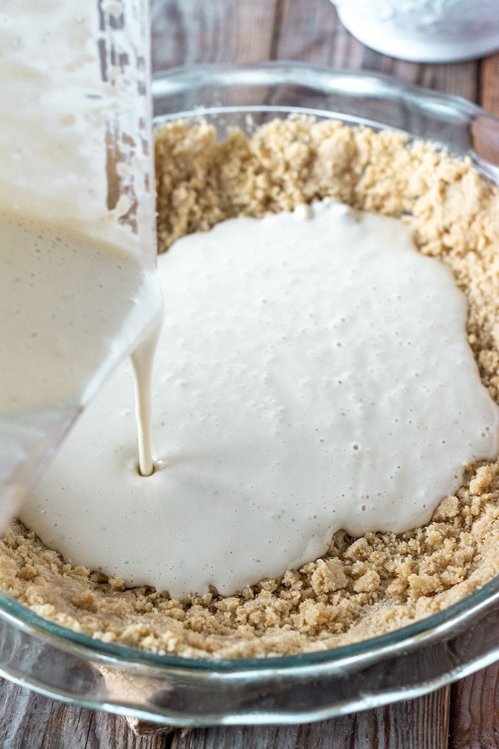 Pouring key lime pie filling in the graham cracker pie crust