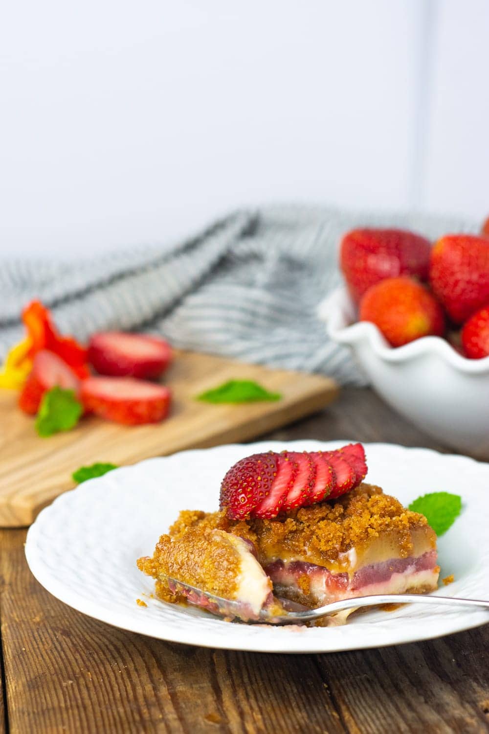 Vegan gluten-Free peanut butter lasagna garnished with strawberry slices on a white plate on a wooden board