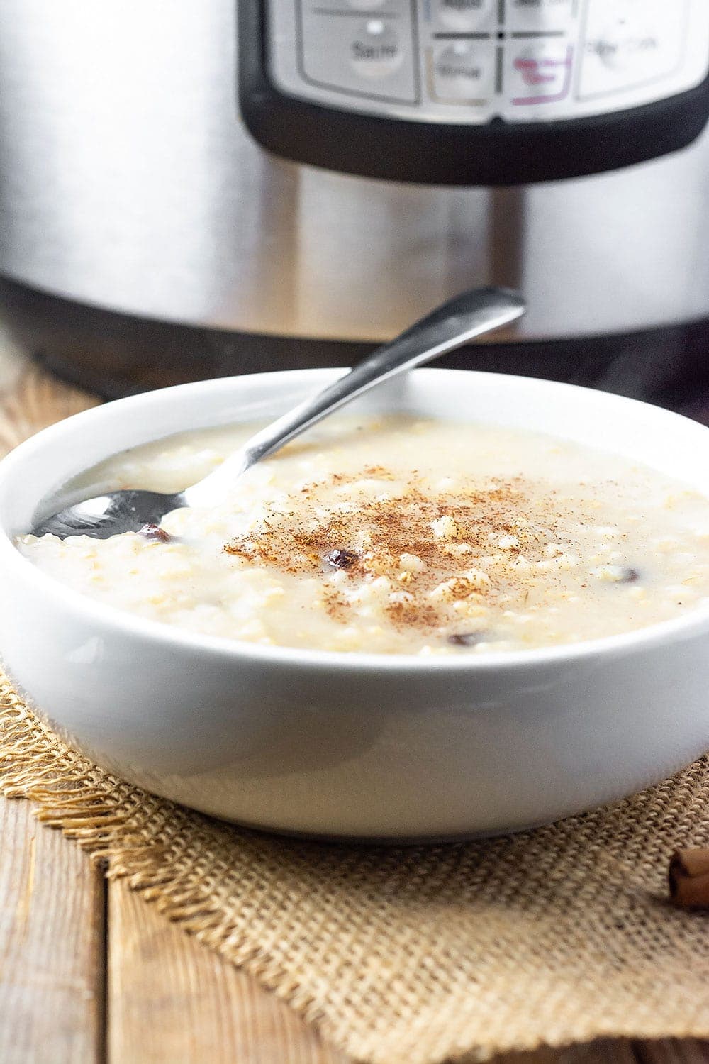 Instant pot creamy rice pudding in a white bowl with the instant Pot in the background on a wooden board