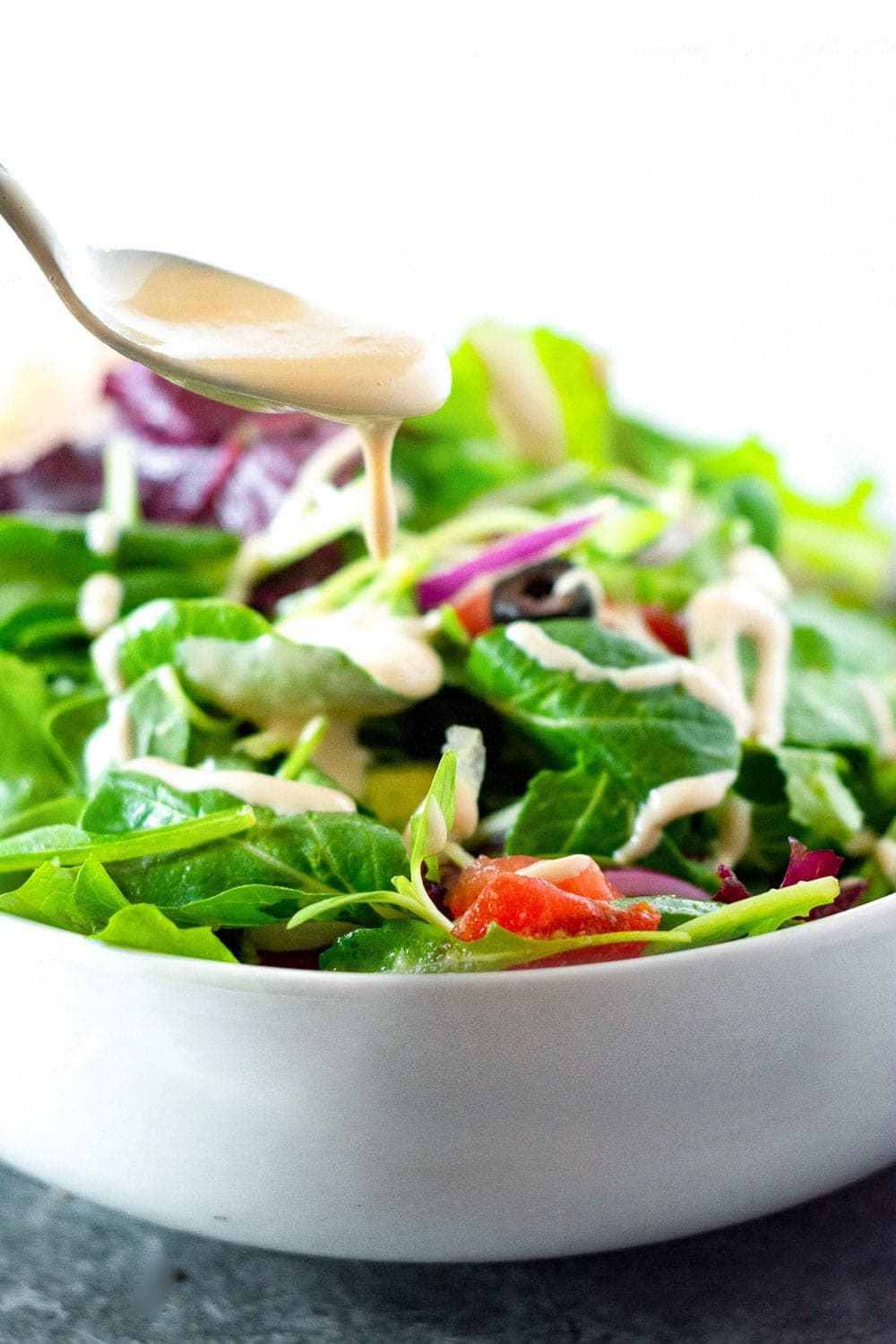 Salad with creamy Asian salad dressing in a white bowl