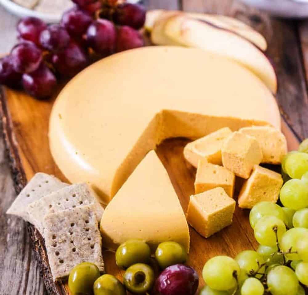 Vegan Cheese Board with cubes of cheese, crackers, olives, grapes