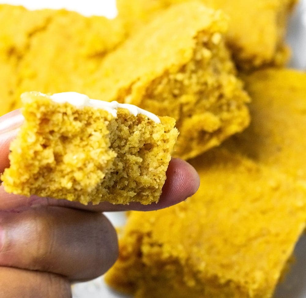 Pumpkin Cornbread slices holding one piece with finger
