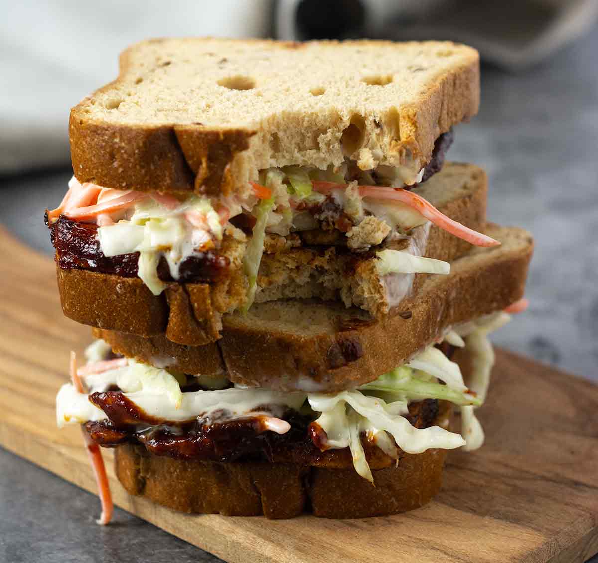 Stacked barbecue tofu sandwiches with the top one having a bite taken