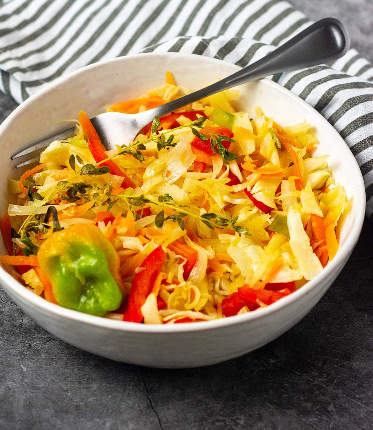 Jamaican steamed cabbage straight on recipe on a grey background with white bowl