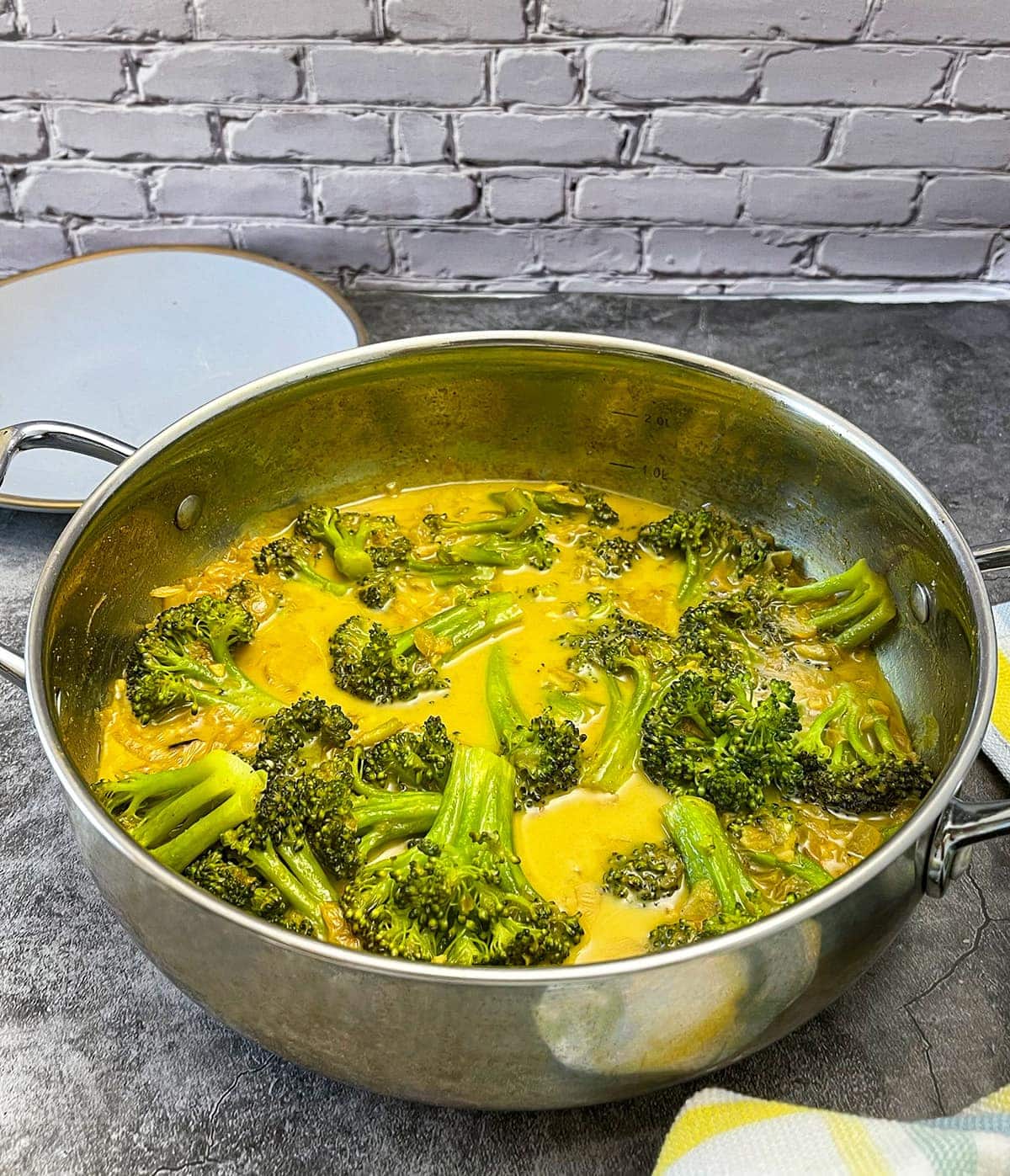 broccoli curry recipe in a silver saucepan on a grey background