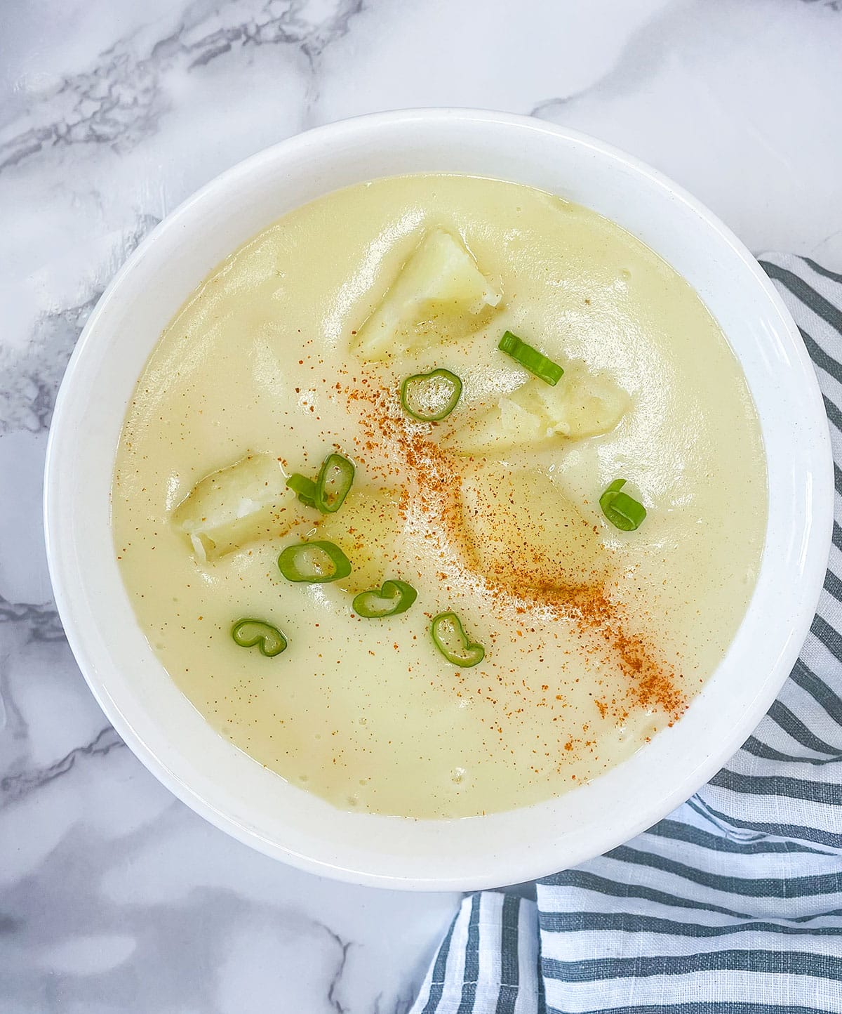 potato soup in the instant pot overlay in a white bowl on a white marble background