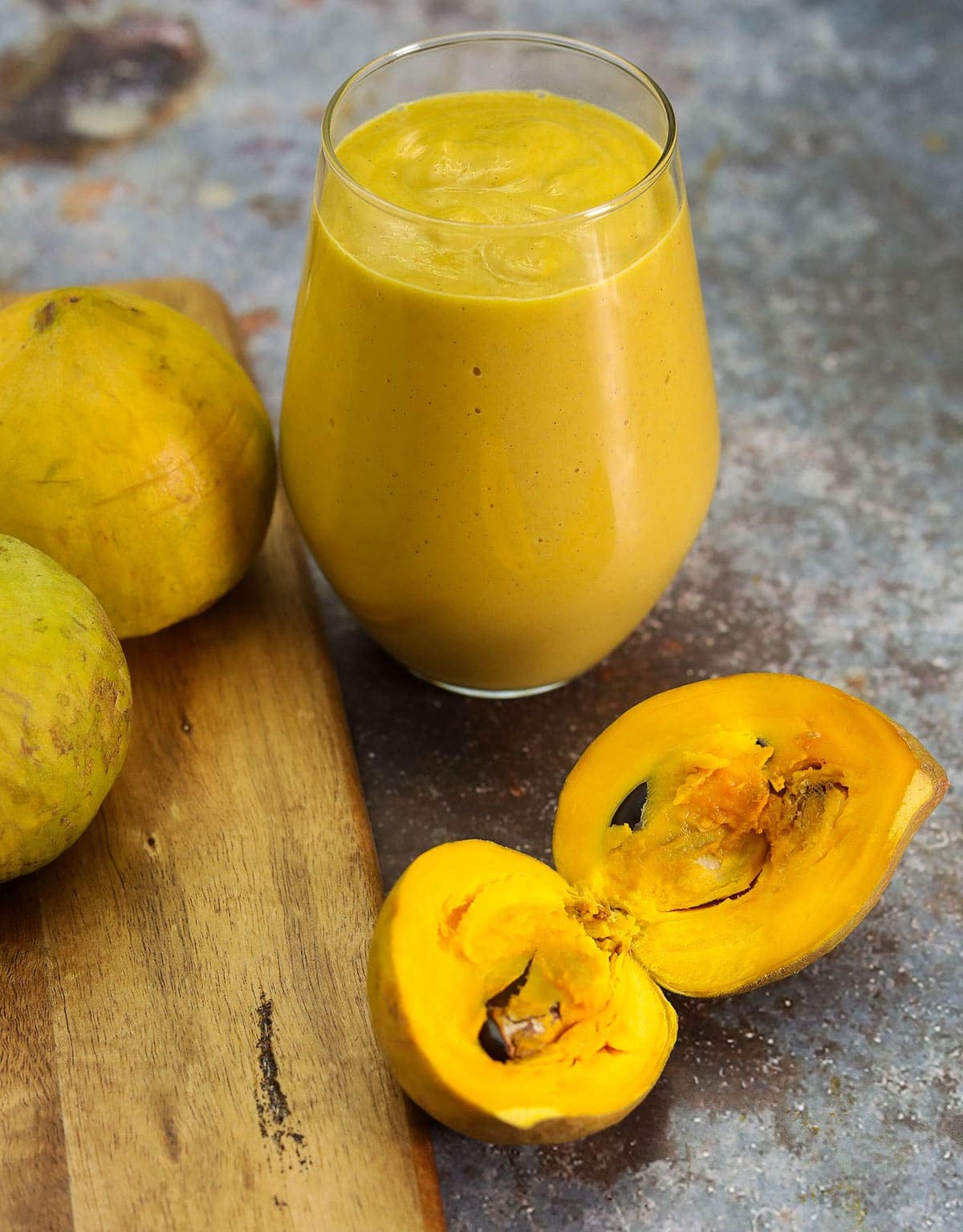 egg fruit nog in a glass on a cutting board surrounded by egg fruits