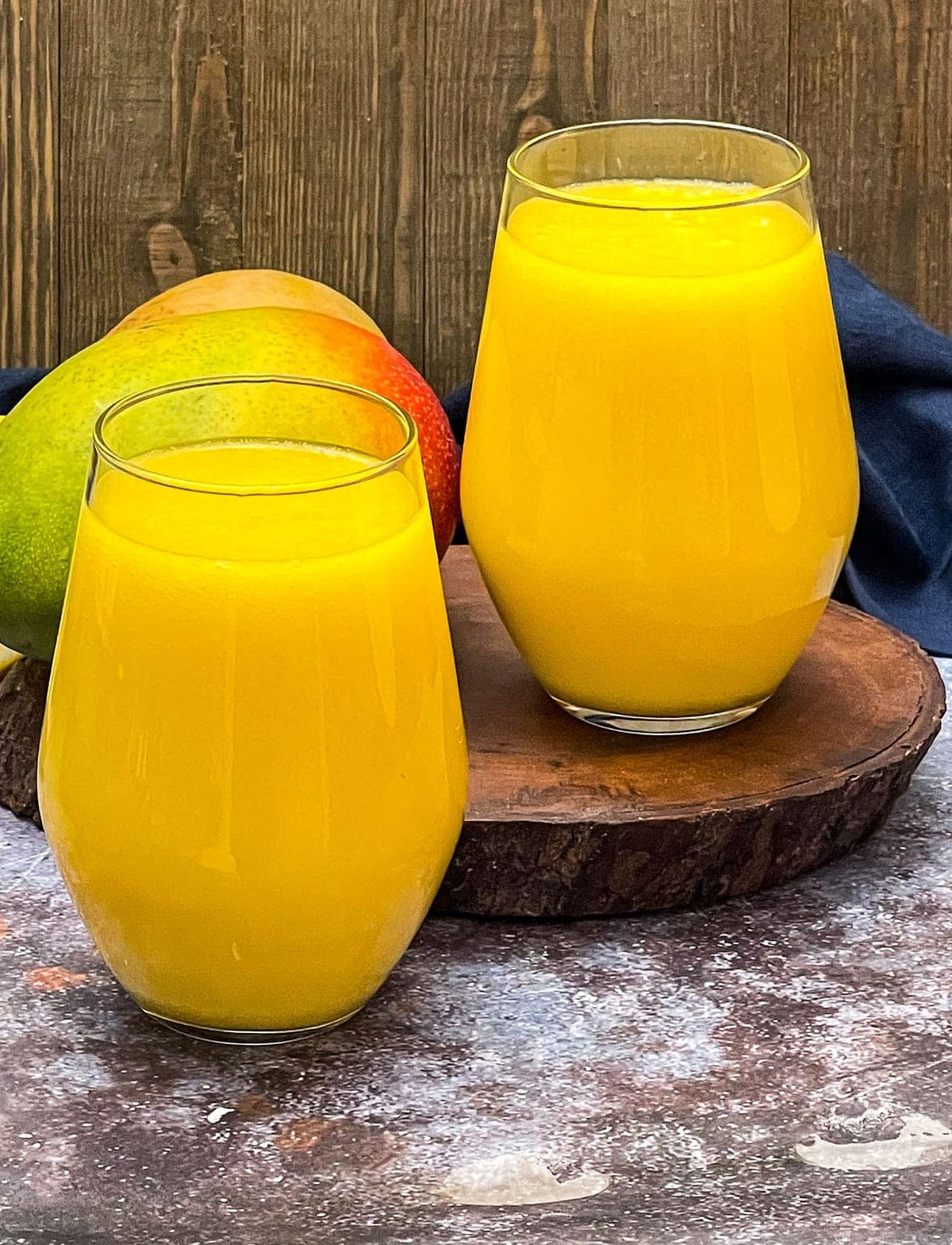 mango drink recipe on a brown and beige concrete 2 glasses wooden background