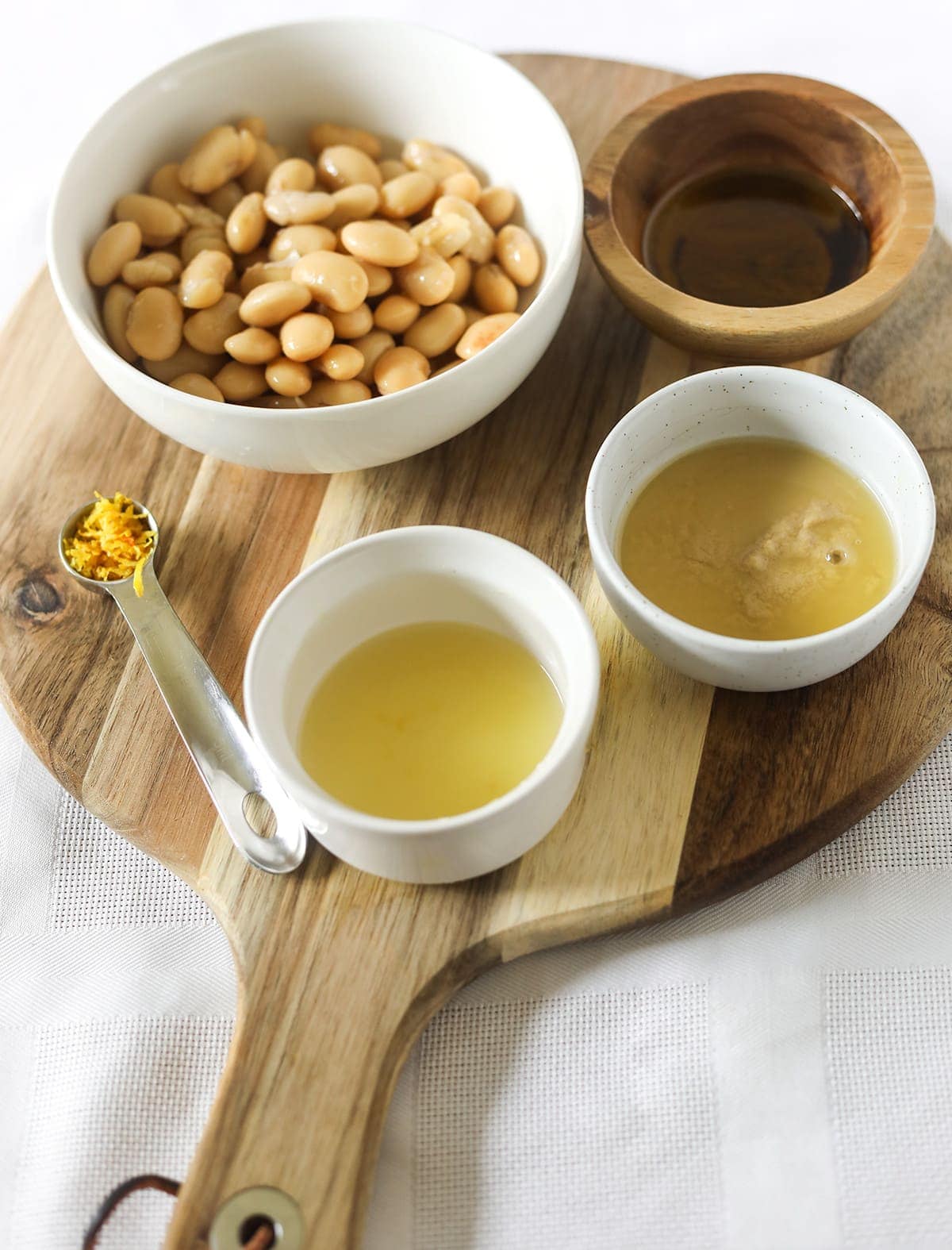 Overlay of hummus ingredients in small bowls on a wooden cutting board
