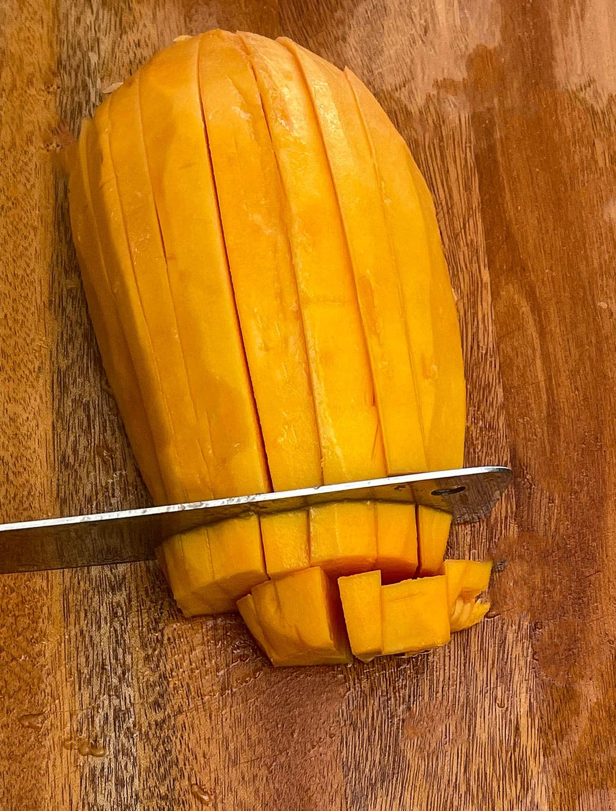 Cubes of papaya on a wooden cutting board