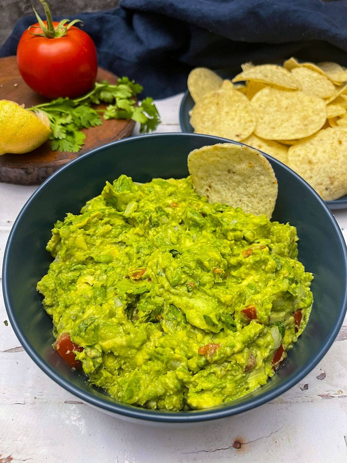 close up guacamole in a blue bowl on white background