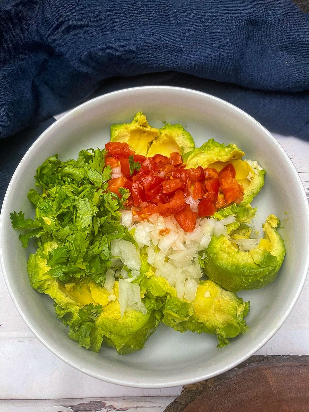 ingredients of guacamole in a white bowl
