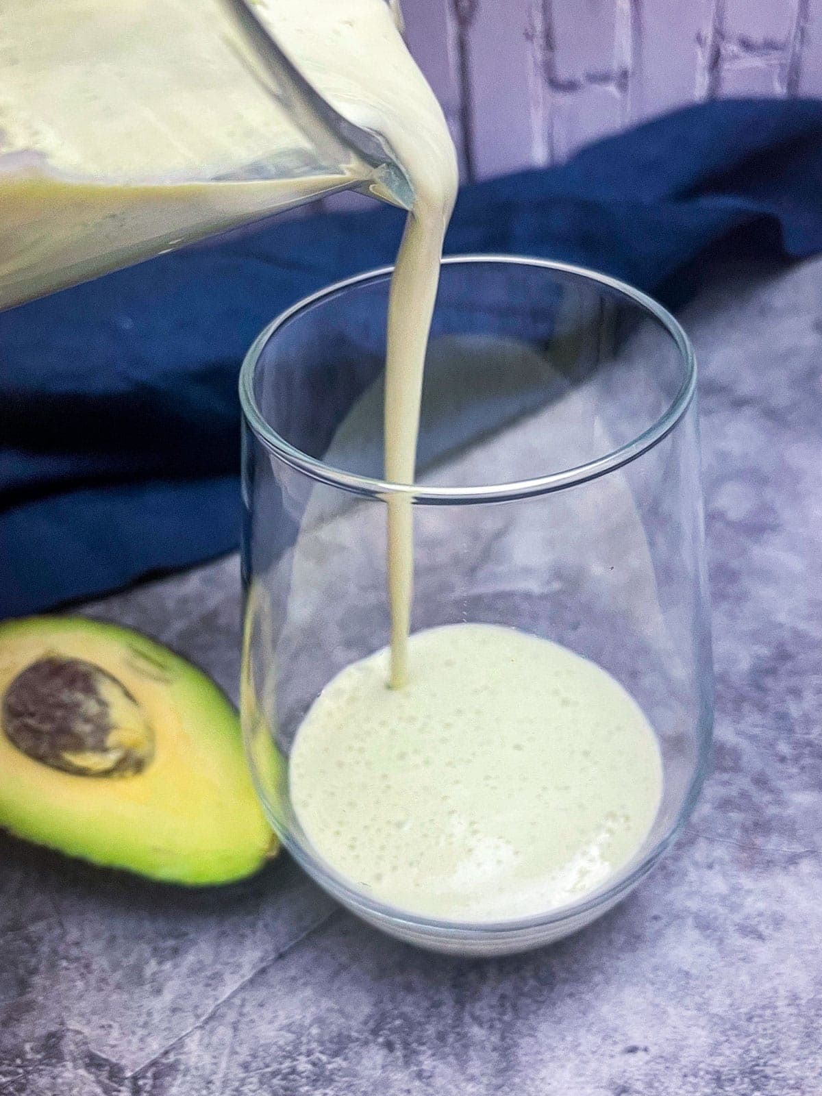 avocado smoothie being poured in a glass