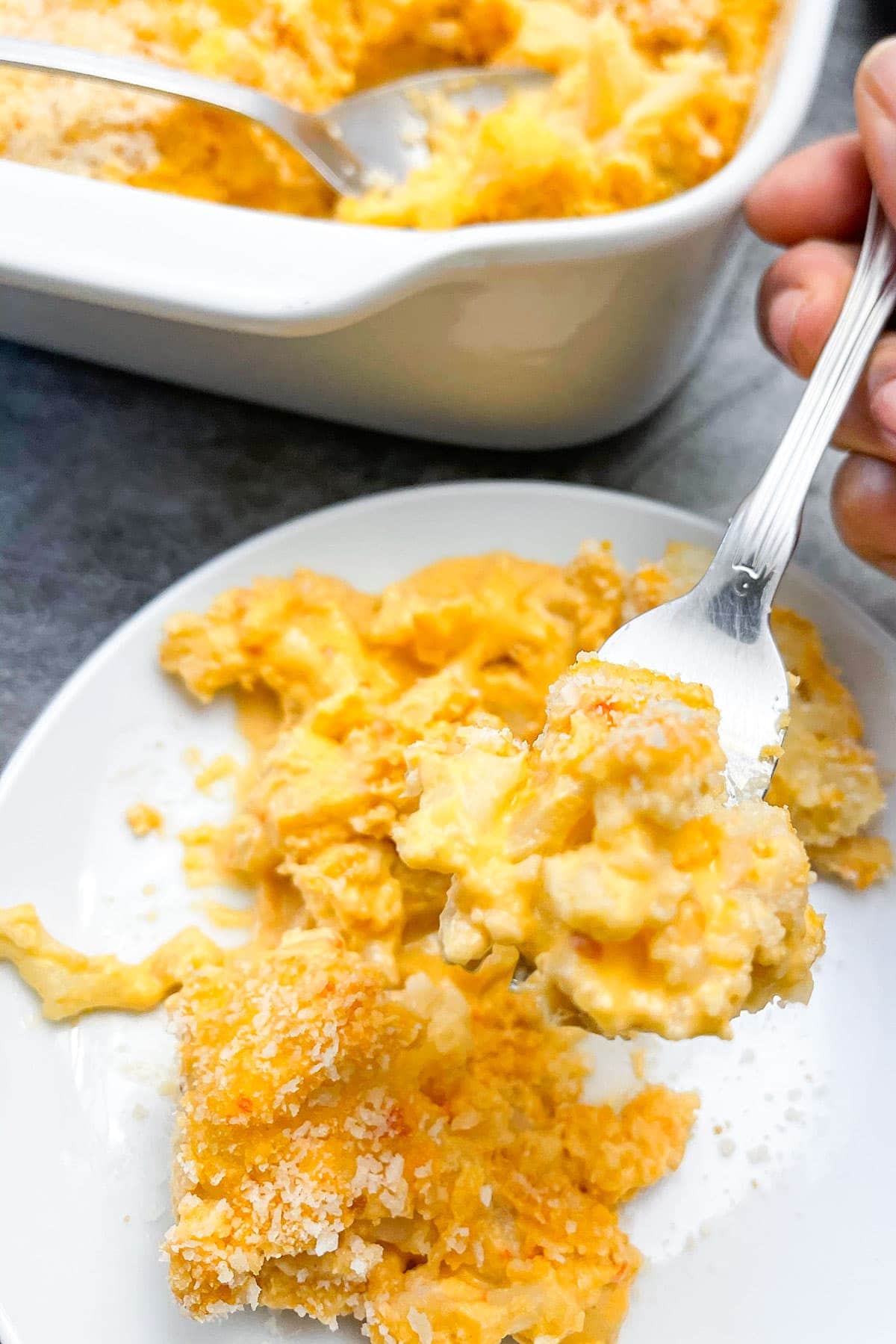 cauliflower mac and cheese on a white plate in the foreground