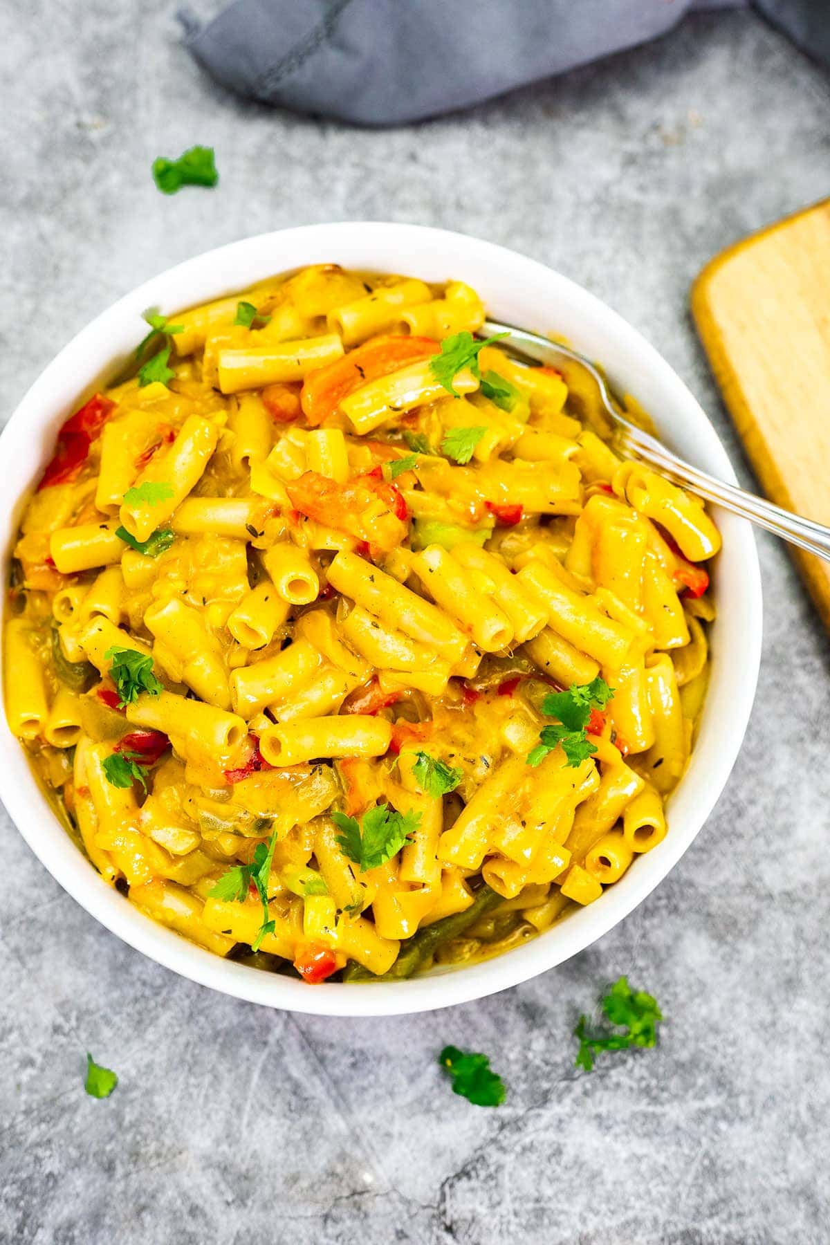 vegan rasta pasta salad on a white plate with a skillet in the background