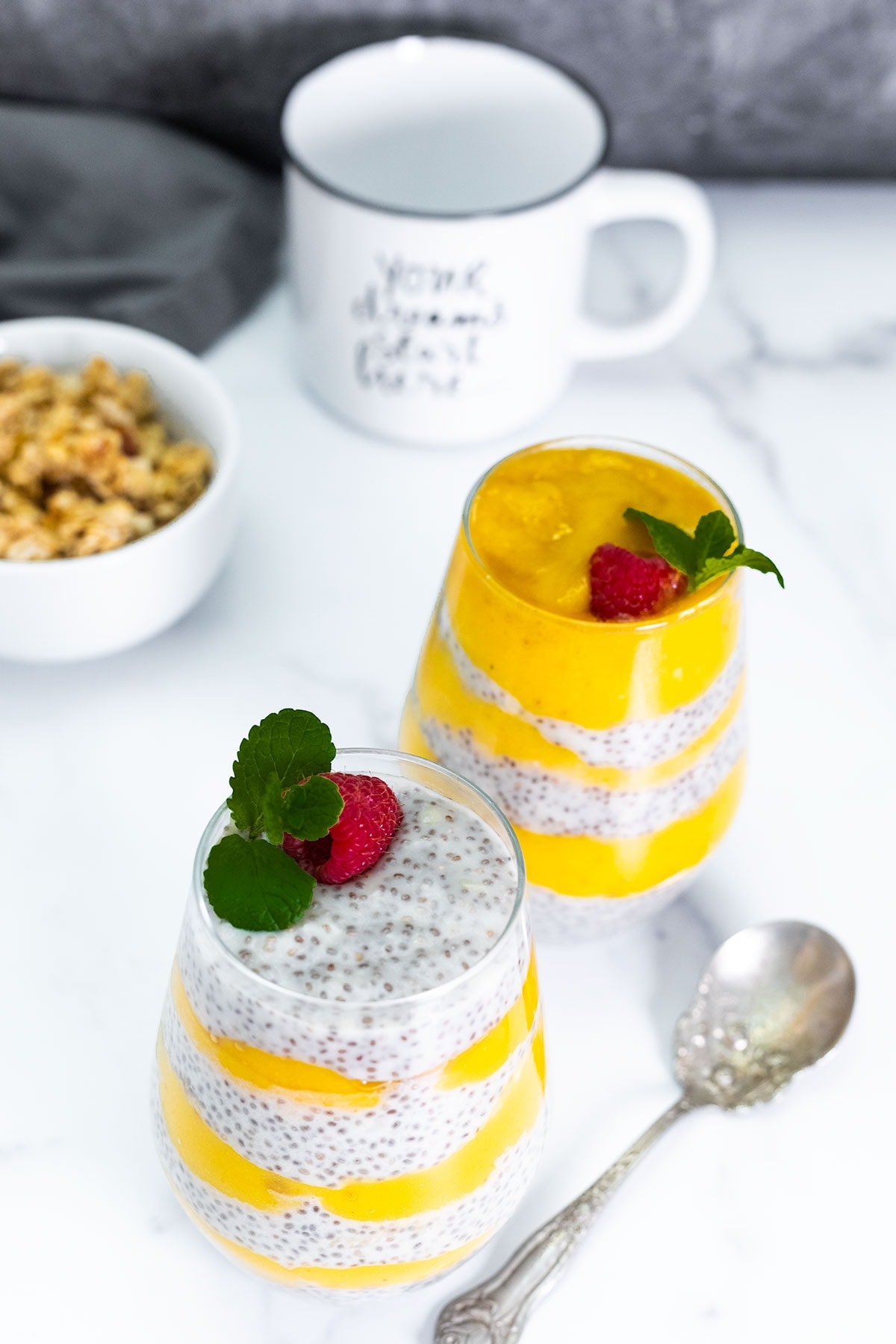 overlay, mango chia pudding into 2 glass jars on a white background