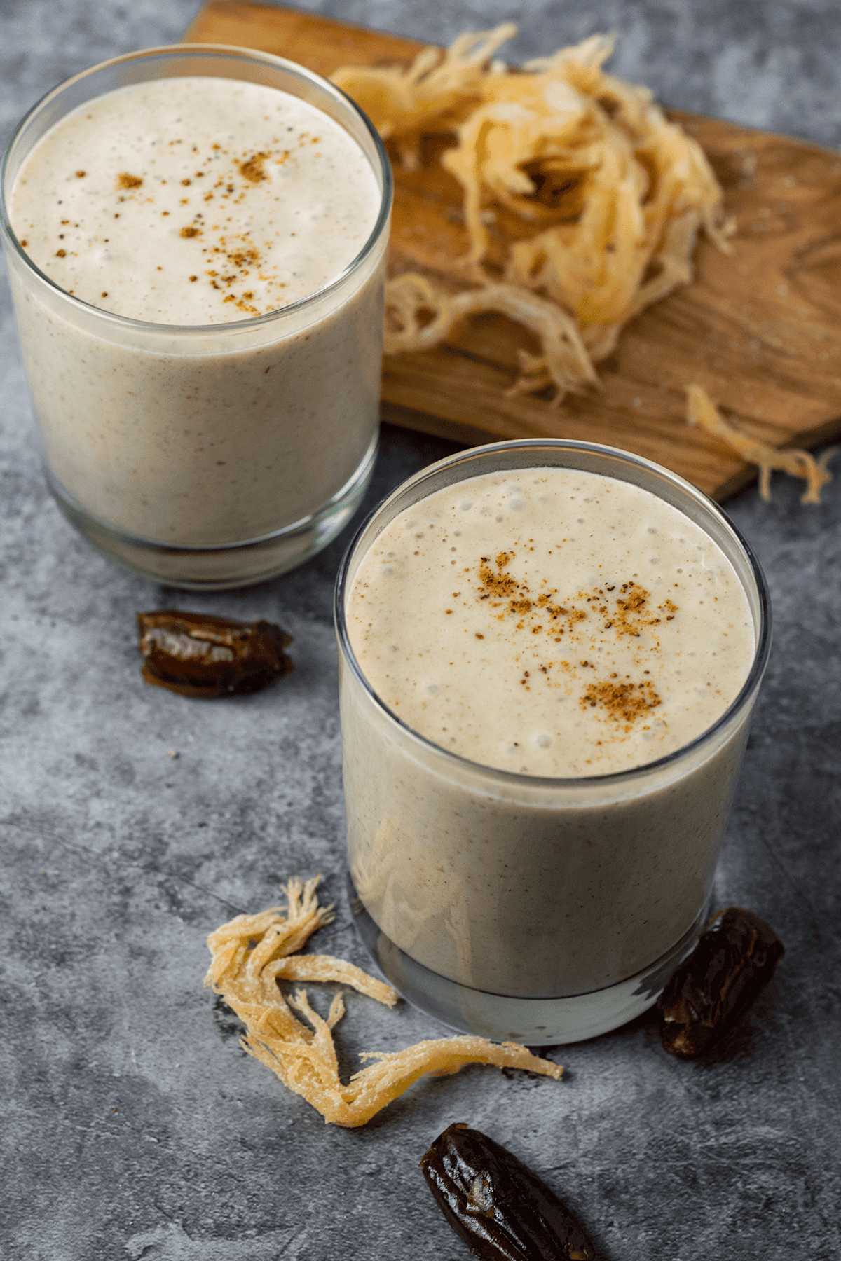 Overlay vegan irish moss (sea moss) in 2 glasses, with fresh irish moss and dates garnish on a grey background