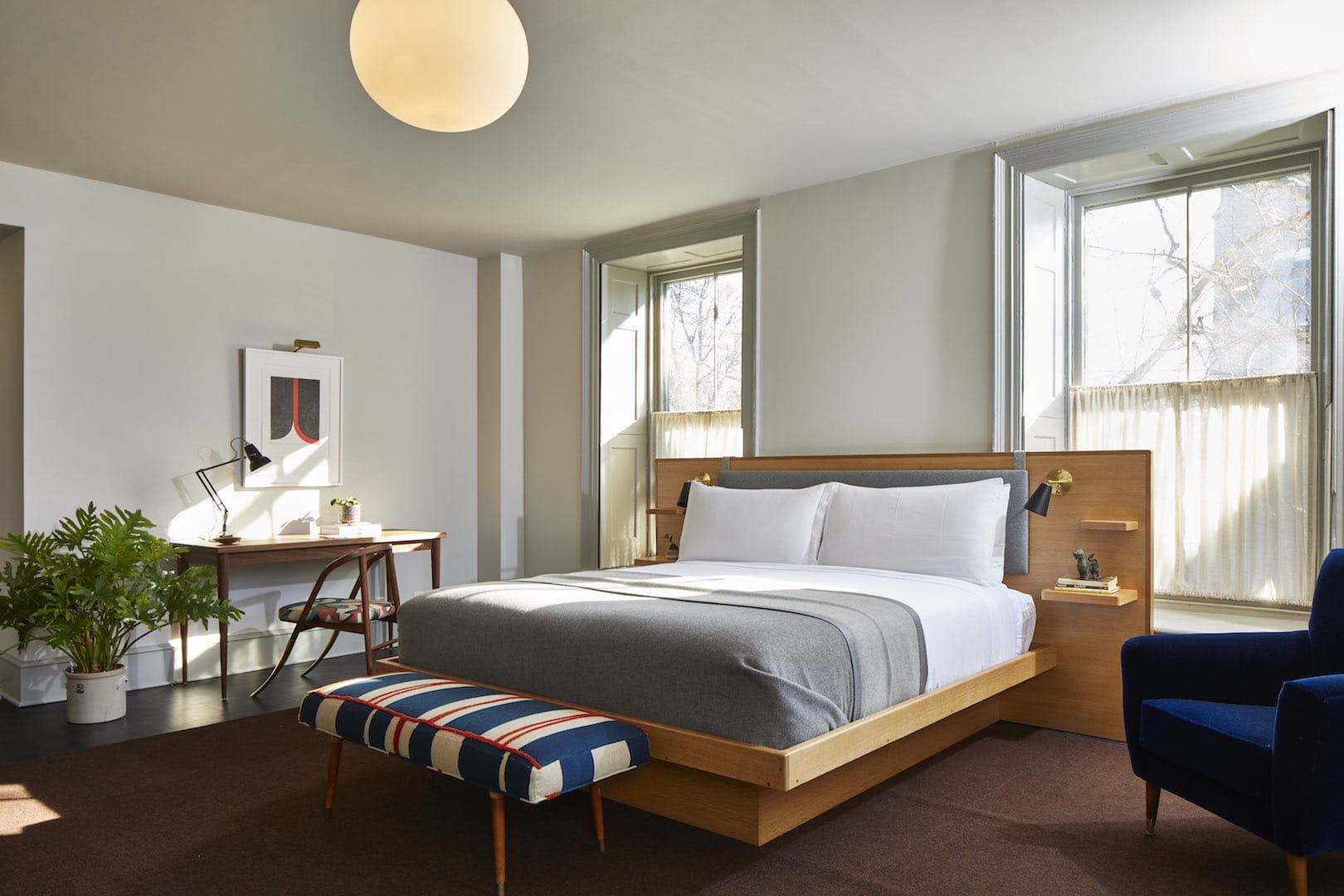A bright and spacious Luxury King Guest Room at Hotel Kinsley's 41 Pearl Street Location. Featuring modern king size bed in front of two large windows, desk space and accent chairs.