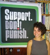 Dovrat from SSDP Israel standing in front of a Support Don't Punish poster.