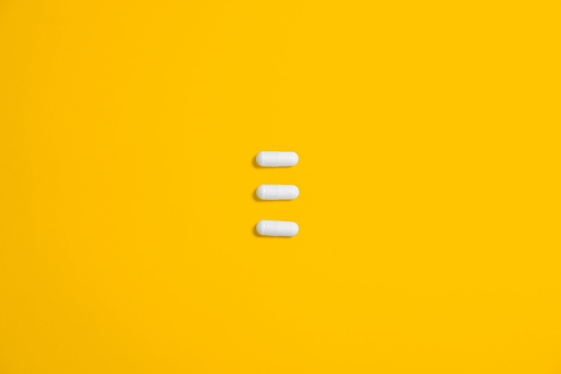 white three oval capsule on yellow canvas