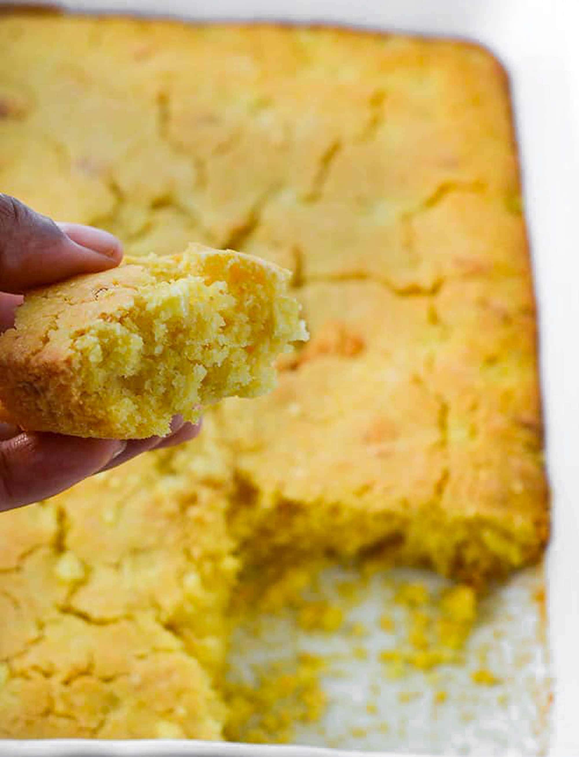 Vegan Gluten-Free Cornbread Casserole overlay in a white casserole pan with a spoonful of cornbread casserole