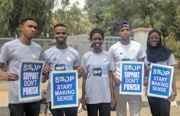 group of five people stood holding signs that read SSDP Support Don't Punish and SSDP Start Making Sense