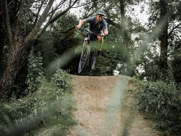 A mountain biker coming over a bump on a trail