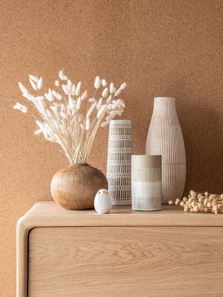 dettaglio di credenza in rovere naturale con vasi di differenti altezze in colori neutri