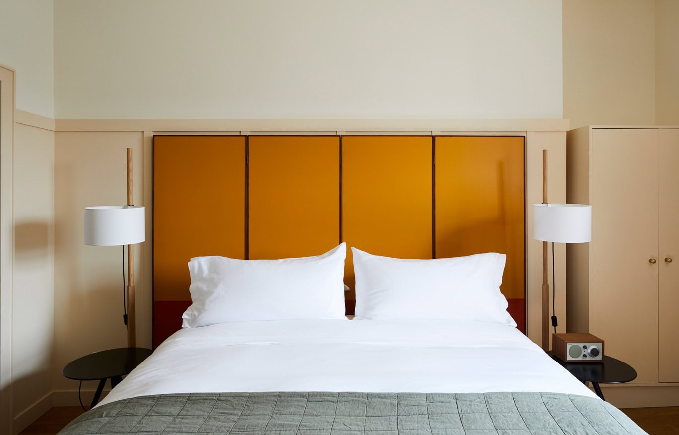 The king size bed with fun, oversized headboard in Hotel Kinsley's Standard King Guest Room at the iconic 301 Wall Street Location.