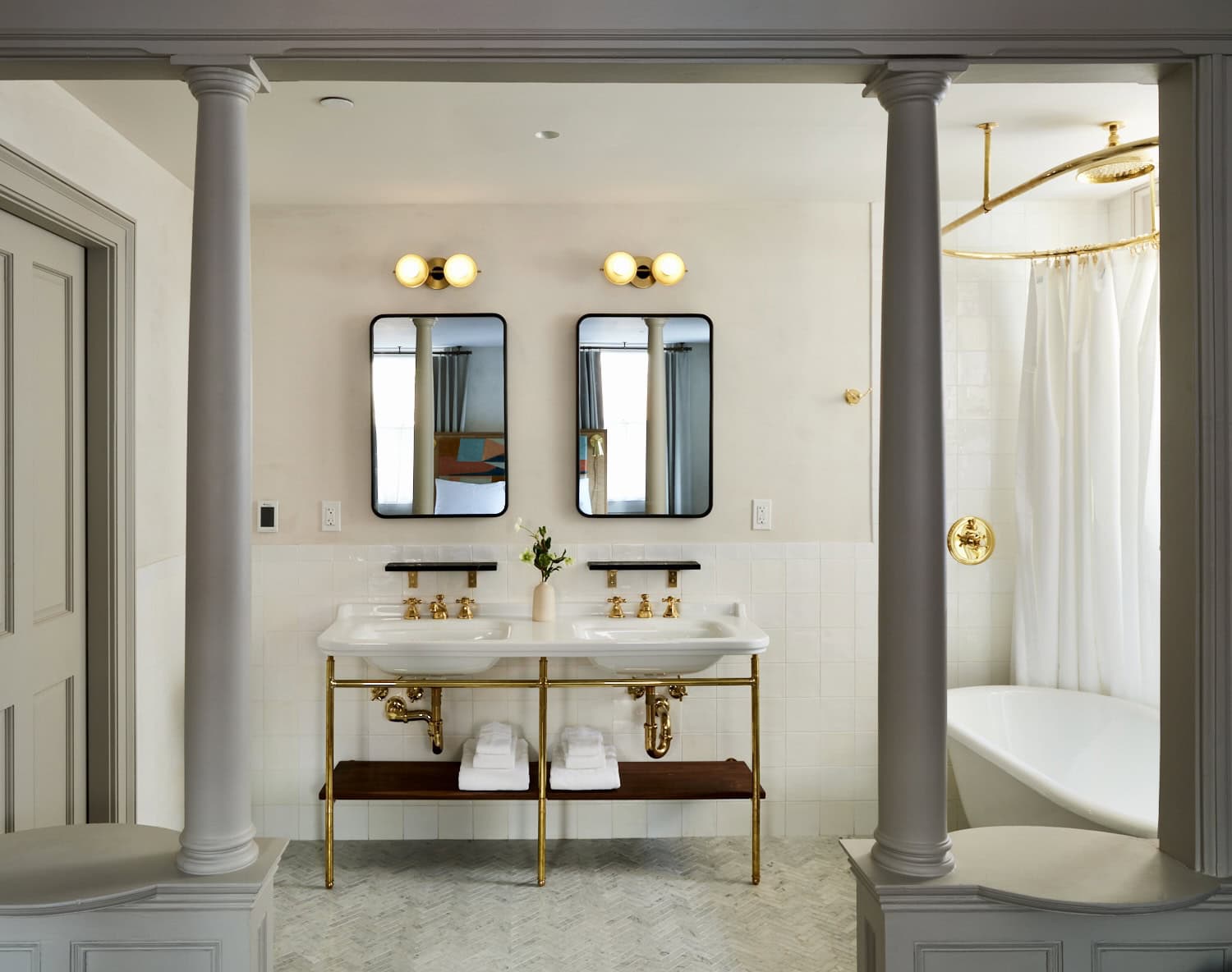 A look inside the spacious bathroom with John Street Luxury Queen Rooms. Complete with double vanity, white roll top soaker tub, heated marble floor tiles and antique brass fixtures.