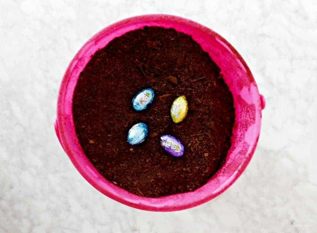 Easter bucket filled with soil with chocolate eggs in dirt