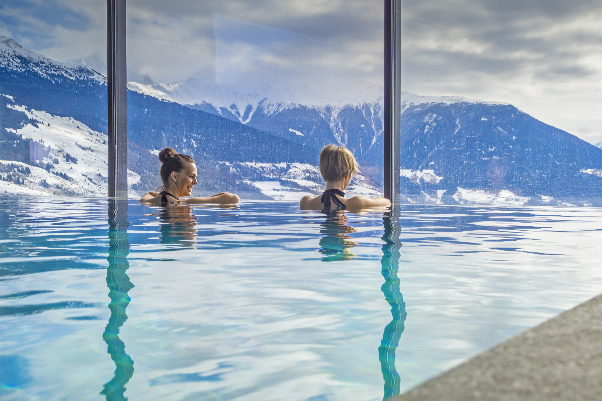 Frauen im Urlaub geniessen Bergpanorama vom Pool aus