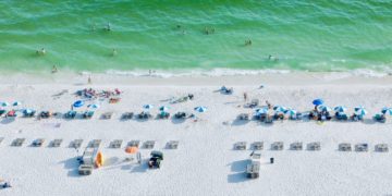 White sand, green surf and beach chairs in a line on the beach at gulf shores