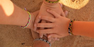 4 hands with friendship bracelets come together the way a blended family does on a familymoon