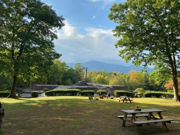 The stone structures of opus 40 with a picnnc table in the foreground and the catskill mountains behind. The foliage is changing color for fall