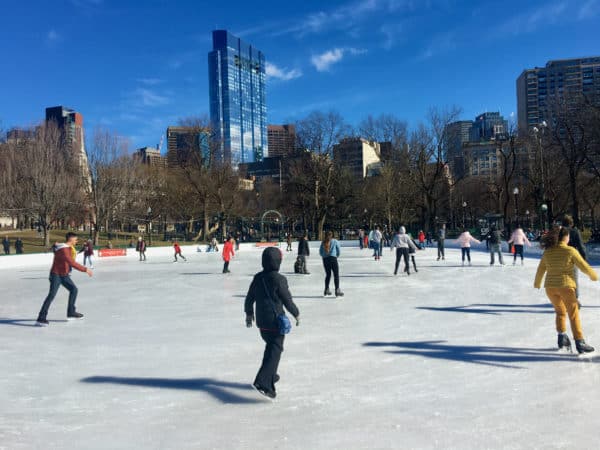 Ice skating on frog pond on the boston common with the city in the background