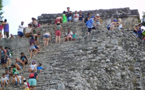 Tourists climb the ruined pyramid at coba
