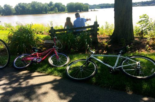 A dad and daughter pause by the susquehana river while bike riding along the capital area greenbelt in harrisburg, pa.