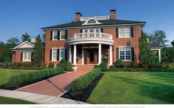 a red brick house with black roof and black shutters