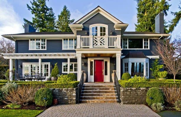 a traditional house with a timeless combination of denim blue wall and ruby red door