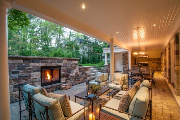 a covered walkout basement patio with fireplace, living area, dining table set, and a small kitchen