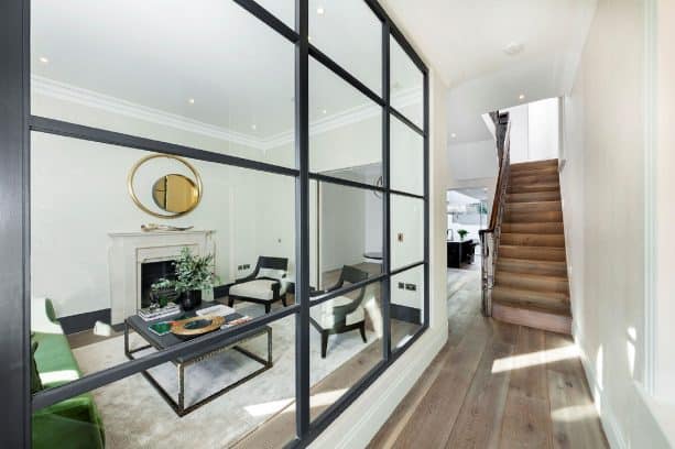 a large glass interior window separating a hallway and a living room