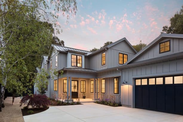 a welcoming two-story cottage in farmhouse style with Summit Grey SW 7669 paint on the board and batten exterior