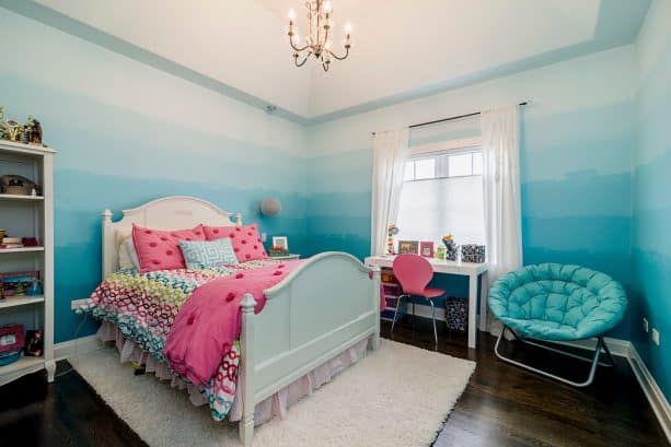 a transitional kids bedroom with ombre blue walls and white curtains