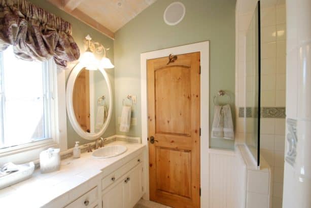 knotty pine wood door paired with white trim to deal with space limitation in a traditional bathroom