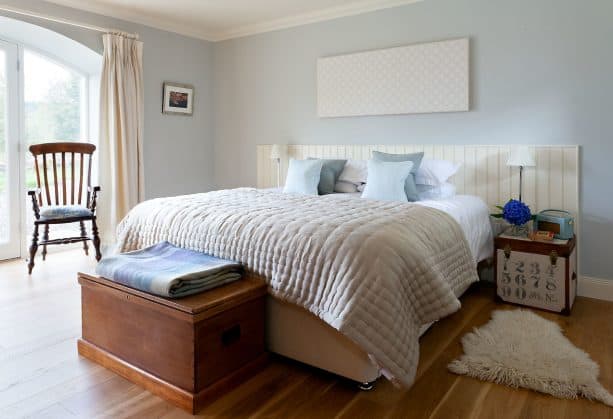 a rustic bedroom with soft blue accents, tan bed, and tan blanket