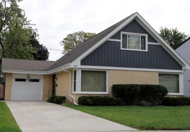 an L-shaped ranch home exterior with cream-painted brick and grey siding combo