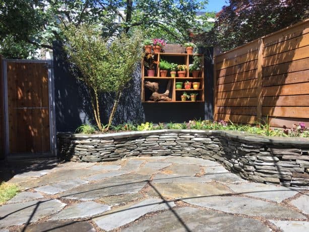 a cinder block wall is painted in slate grey color after a garden makeover